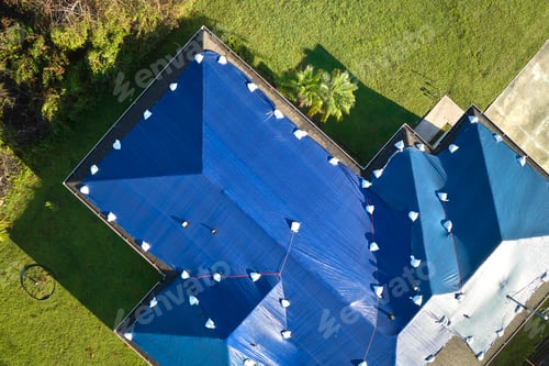 Preview: Top view of leaking house roof covered with protective tarp