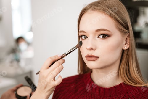 Preview: process of face makeup brush alignment of the face tone on a beautiful young woman model blonde
