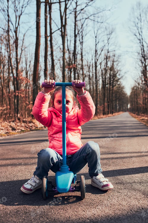 Preview: Little girl playing in the park, riding a scooter, having fun on sunny autumn day