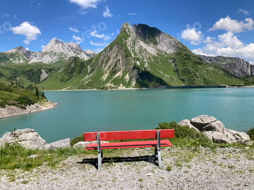 Preview: A red bench in front of a mountain lake