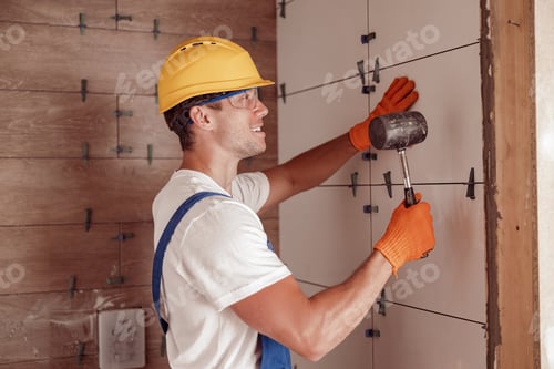 Preview: Male builder installing ceramic wall tile in house