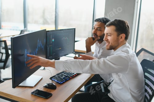 Preview: Two successful trader in formalwear pointing at display