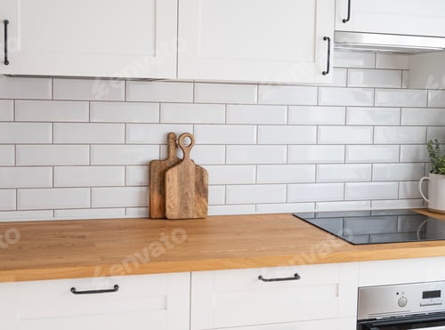 Preview: Cozy white kitchen with wooden countertop, flower and cutting boards in a minimalist interior