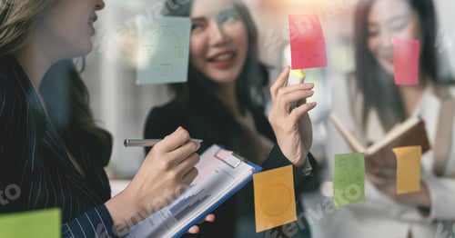 Preview: businesswoman creative team using post it notes in glass wall plan to success.