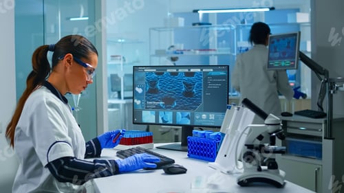 Preview: Chemist doctor holding test tube with blood sample entering datas in pc