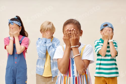 Vista previa: Four Afraid Preteen Children Covering Eyes with Hands in Studio