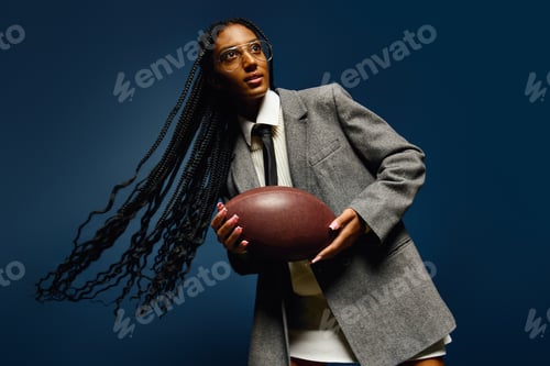 Preview: A young woman wears a tailored blazer and holds a football while showcasing her vibrant personality.