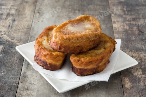 Preview: Delicious french toast with sugar and cinnamon resting on a wooden table