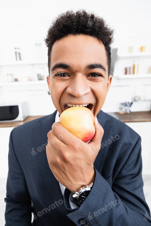 Preview: happy african american businessman eating apple