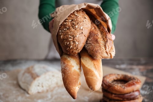 Preview: Cropped image of female baker showing bag with bread
