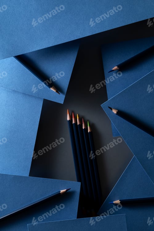 Preview: Art composition with colored pencils and sheets of indigo paper lying on the table in the dark key