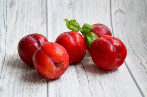 Preview: red plums on white wooden background