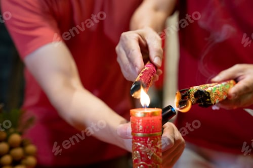 Preview: Hand holding joss sticks and candle as prayer and offering to the Gods