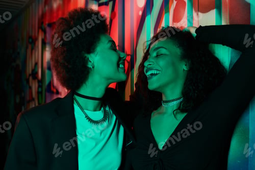 Preview: Joyful friends sharing a vibrant moment against a colorful mural in a lively urban setting