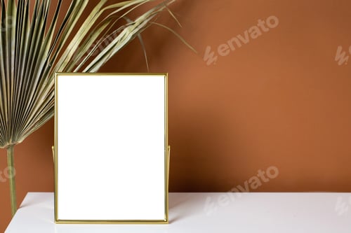 Preview: Gold frame copyspace and plant on white table with dark orange wall background