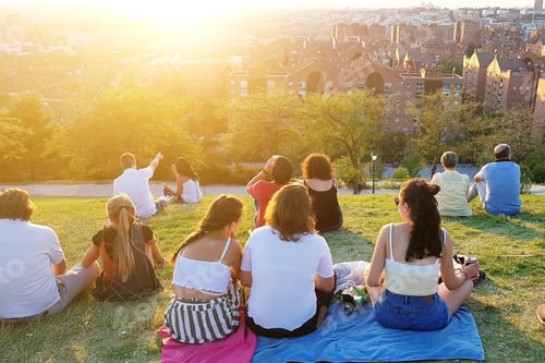 Preview: People from behind sitting on the grass looking the sunset