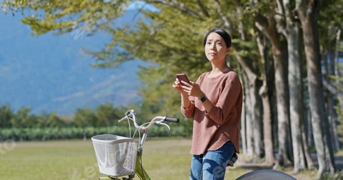 Preview: Woman ride a bike and use of mobile phone to search for location