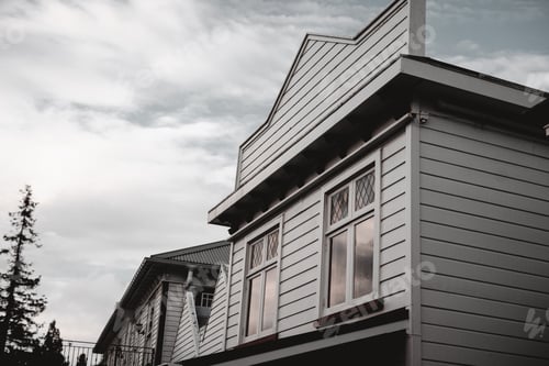 Preview: facade of old wooden house with square white windows in nice quiet village far from civilization