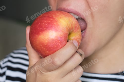 Preview: Close-up of a person biting into a fresh apple, highlighting the crisp texture and juiciness