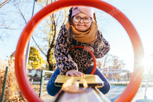 Preview: Brave girl with Down syndrome leaning forward on seesaw