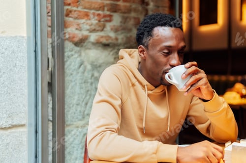 Preview: African american man enjoying and drinking a coffee while sitting at coffee shop