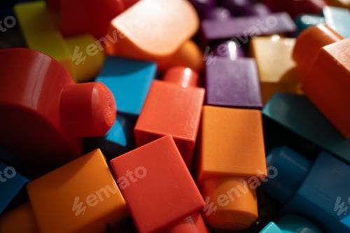 Preview: Closeup multicolored glossy plastic blocks stacked in warm light with shallow focus and soft shadows