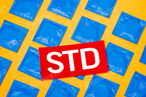 Preview: top view of paper with std lettering near blue packs with condoms isolated on orange
