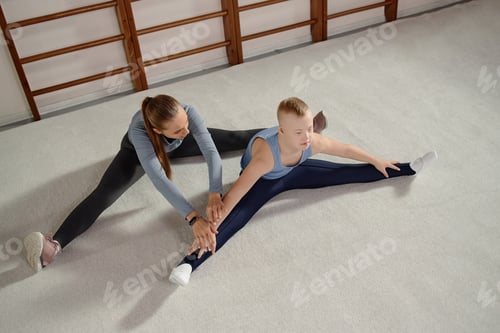 Preview: Child with Down Syndrome Stretching with Female Instructor Indoors