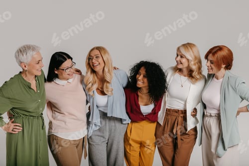Preview: Multi-ethnic group of happy mature women embracing against grey background