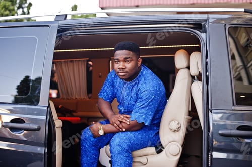 Preview: Black man wearing cool traditional clothes sitting in the minivan.