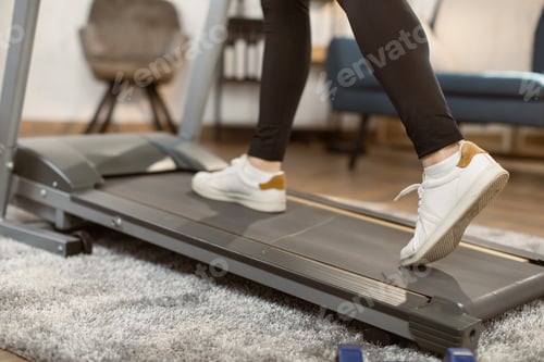 Preview: Close up of athletic feet running on treadmill at home.