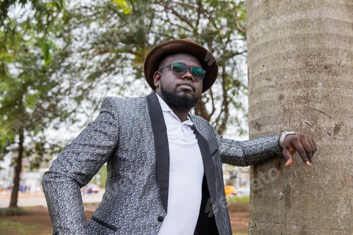 Preview: Young thoughtful African man poses in his city park. Loneliness concept