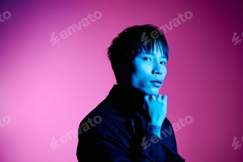 Preview: Stylish young asian man poses confidently against a vibrant purple backdrop