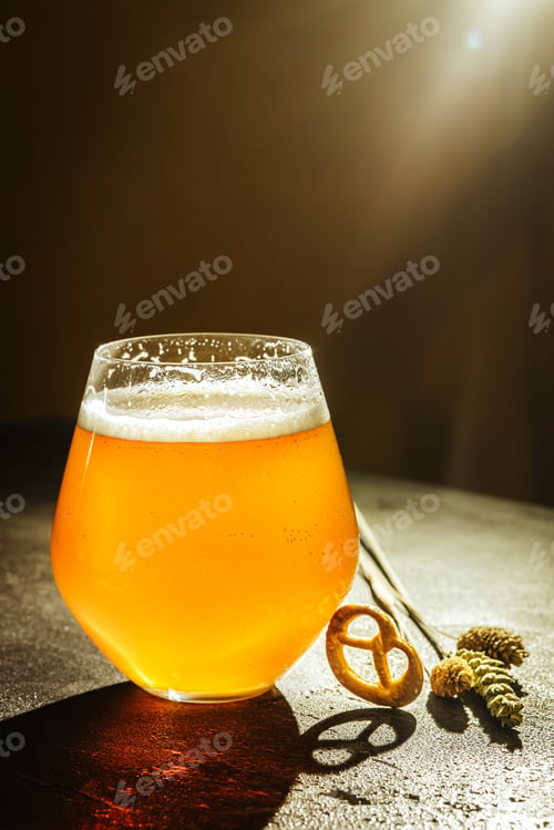 Preview: Close up glass of non-filtered light beer with pretzels, festive dinner party celebration weekend