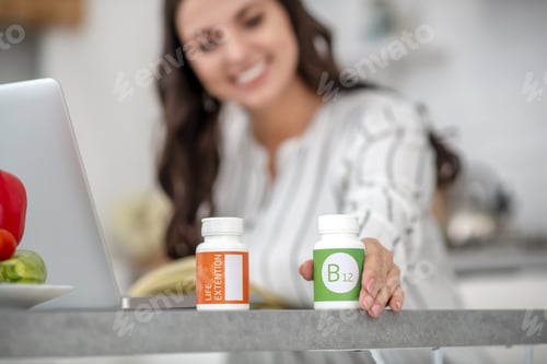 Preview: Dark-haired woman in a striped blouse choosing vitamins