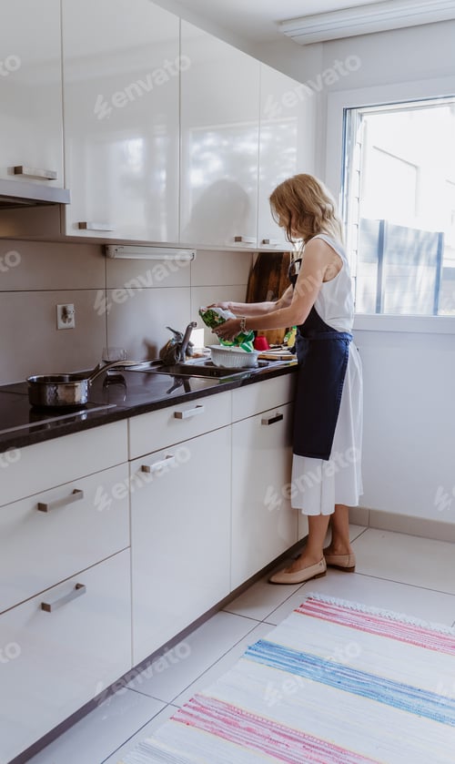 Preview: Young woman wearing apron making lunch for family at home kitchen