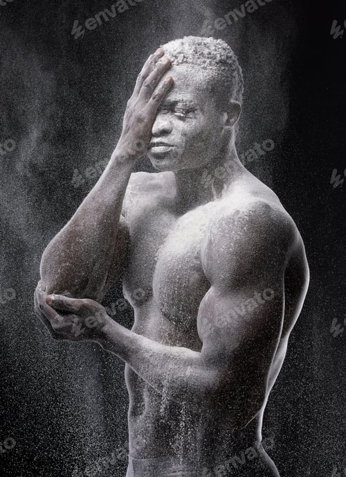 Preview: Artistic shot of a muscular young man posing with white powder in studio against a dark background