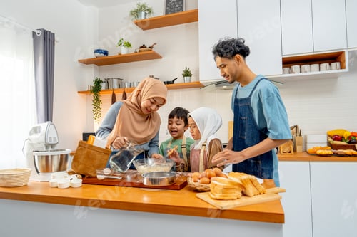 Preview: Muslim mother pour the water in jar to mixed flour in the bowl for teach her child to make bakery