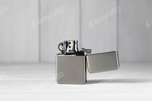 Preview: Gray metallic cigarette lighter on white wooden table