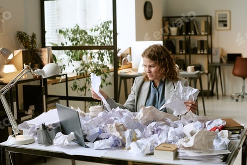Preview: Young Woman Analyzing Documents at Desk in Modern Office