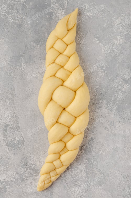 Preview: Raw loaf of challah Jewish bread on a light gray background. Top view, copy space.