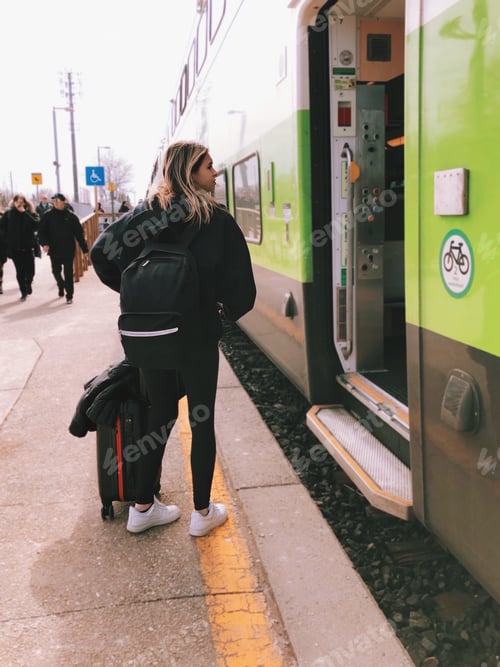 Preview: Young girl with a suitcase and backpack is getting on a train, public transportation