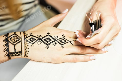 Preview: Artist applying henna tattoo on women hands. Mehndi is traditional Indian decorative art. Close-up
