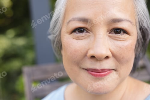 Preview: Outdoors, senior Asian female smiling gently at camera