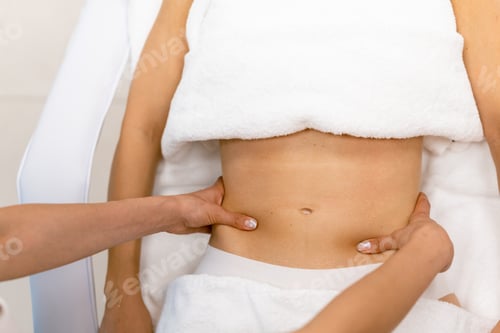 Preview: Middle-aged woman having a belly massage in a beauty salon. Body care treatment in a beauty centre.