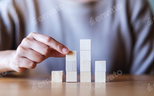 Preview: Closeup image of a hand stacking and picking blank wooden cube block