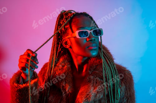 Preview: Black ethnic woman with braids with red and blue led lights, studio shoot with sunglasses