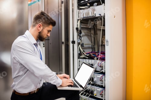 Preview: Technician using laptop while analyzing server