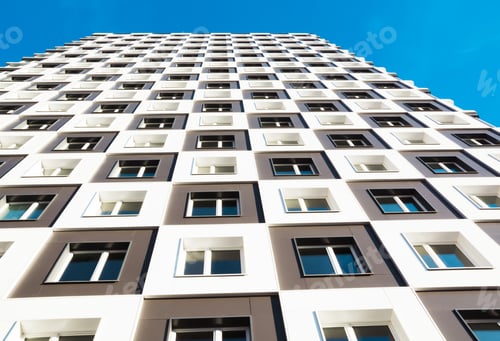 Preview: Modern and new apartment building. Photo of a tall block of flats against a blue sky.