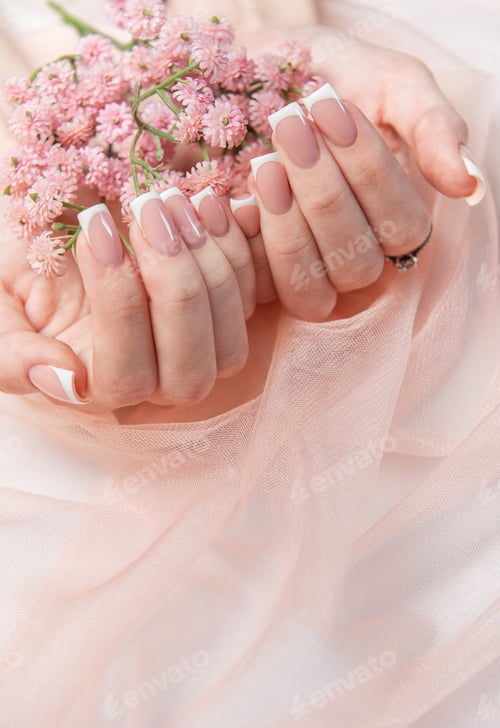 Preview: Woman showing french manicure holding pink flowers on pink tulle